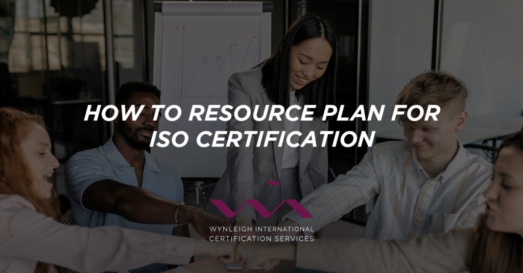 A banner image designed specifically for the Wynleigh International brand. The background image shows a diverse team of business professionals working on resource planning for a project. There is a text overlay that reads: "How to Resource Plan for ISO Certification"